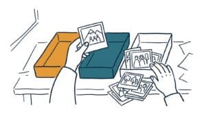 Marker doodle of two hands sorting loose photo prints into coloured trays, one print held up to the light