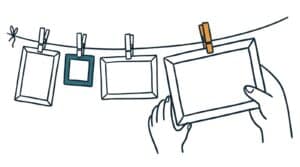 Marker doodle of empty picture frames in several sizes pegged to a washing line, a hand steadying the largest